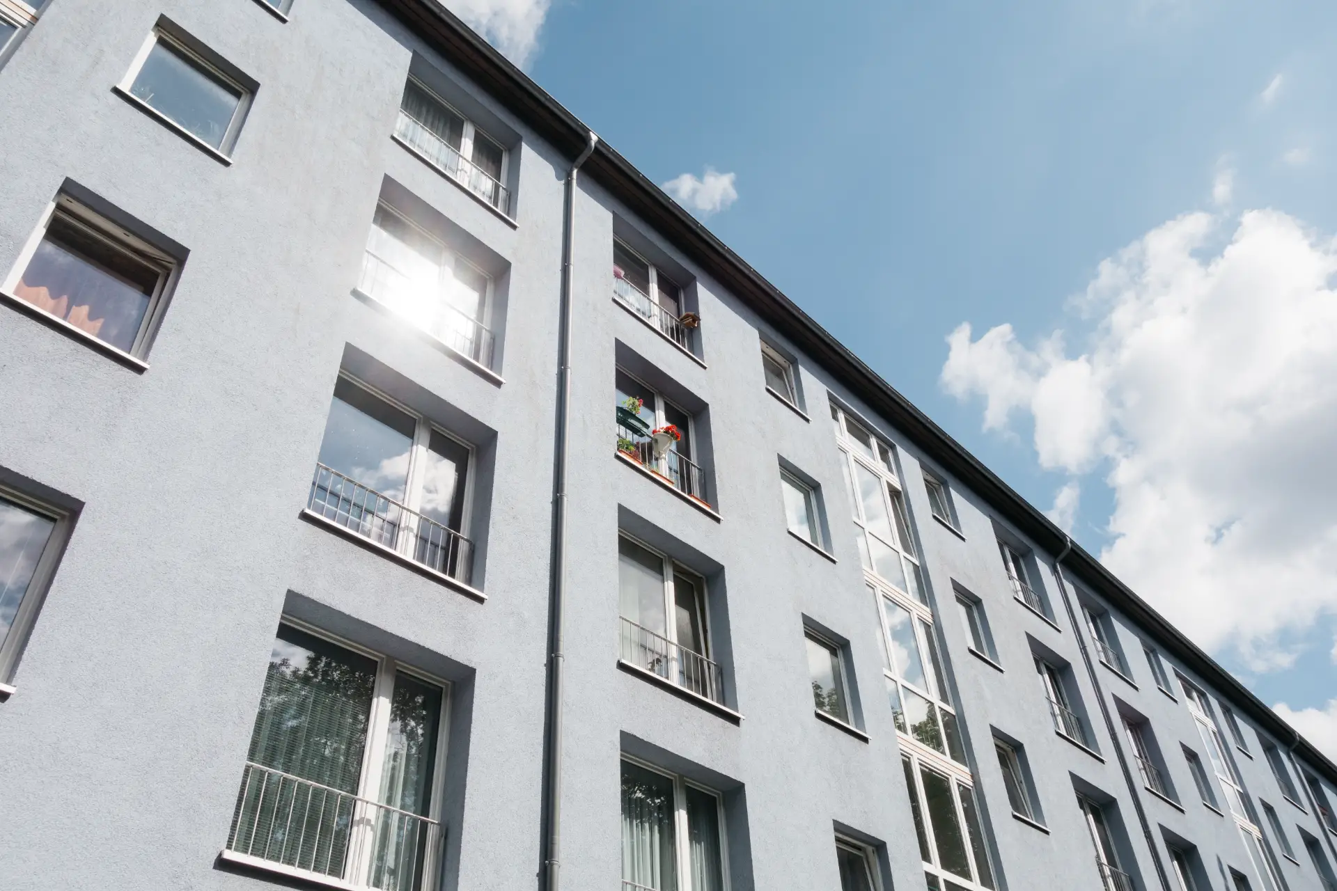 Horsens bygningsfacade med vinduer og sollys, specialiseret i teknisk service og vedligeholdelse.