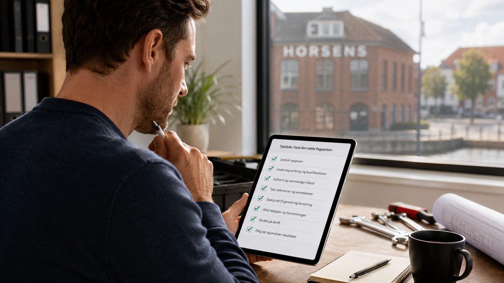 En mand sidder på sit kontor i Horsens og bruger en tablet med en tjekliste til fagfolk.
